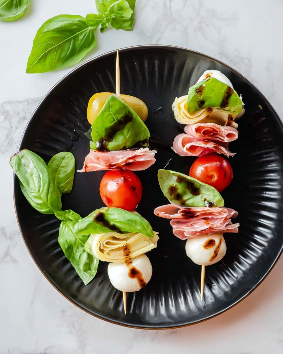 A black plate on a white marbled surface holds four small skewers arranged neatly. Two skewers have three layers: a green olive at the bottom, followed by a pale yellow artichoke heart, and topped with a bright red cherry tomato. The other two skewers each start with a folded slice of pinkish-red cured meat, followed by a fresh green basil leaf, and finished with a white mozzarella ball lightly drizzled with brown balsamic glaze, all secured by a short wooden pick. Bright green basil leaves are scattered near the plate. photo taken with an iphone --ar 4:5 --v 7