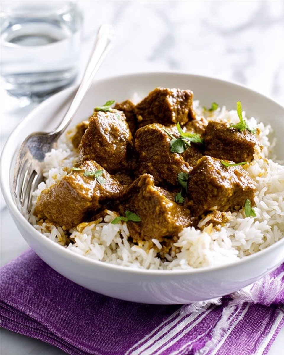 A white bowl filled with a layer of fluffy white rice as the base, topped with several pieces of brown, thick curry-coated meat chunks scattered unevenly. Small green herbs are sprinkled on top of the meat, adding a touch of color. The bowl is placed on a white marbled surface with a purple and white striped cloth underneath. A silver fork lies next to the bowl, with a clear glass of water blurred in the background. Photo taken with an iphone --ar 4:5 --v 7