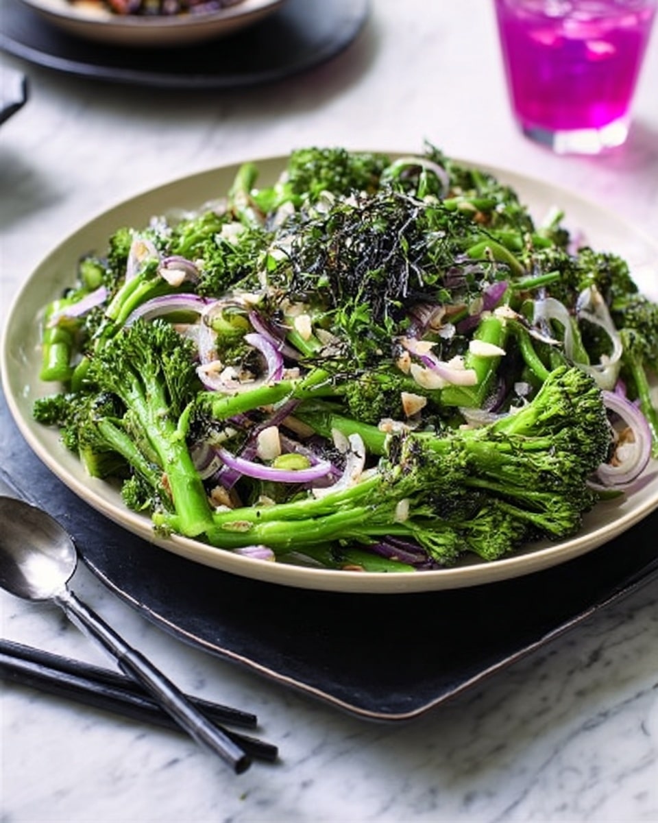 A large white shallow plate filled with a fresh green salad made of broccolini stalks and small florets, mixed with thin slices of cooked purple onions, and sprinkled with small white almond flakes. The salad is topped with some dark green finely chopped herbs. The plate sits on a black square plate on a white marbled surface. Nearby are a pair of black chopsticks and a white spoon. In the background, there is a glimpse of a purple pink drink in a clear glass. photo taken with an iphone --ar 4:5 --v 7