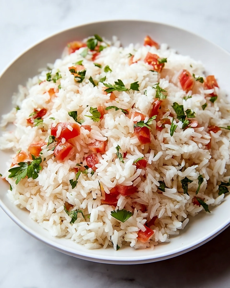 A top view of a white bowl filled with a single layer of cooked white rice mixed evenly with small chopped pieces of red tomatoes and bits of green parsley leaves scattered throughout. The rice grains have a soft and fluffy texture, while the tomatoes add bright splash of red and the parsley adds fresh green accents. The white bowl sits on a white marbled surface. photo taken with an iphone --ar 4:5 --v 7