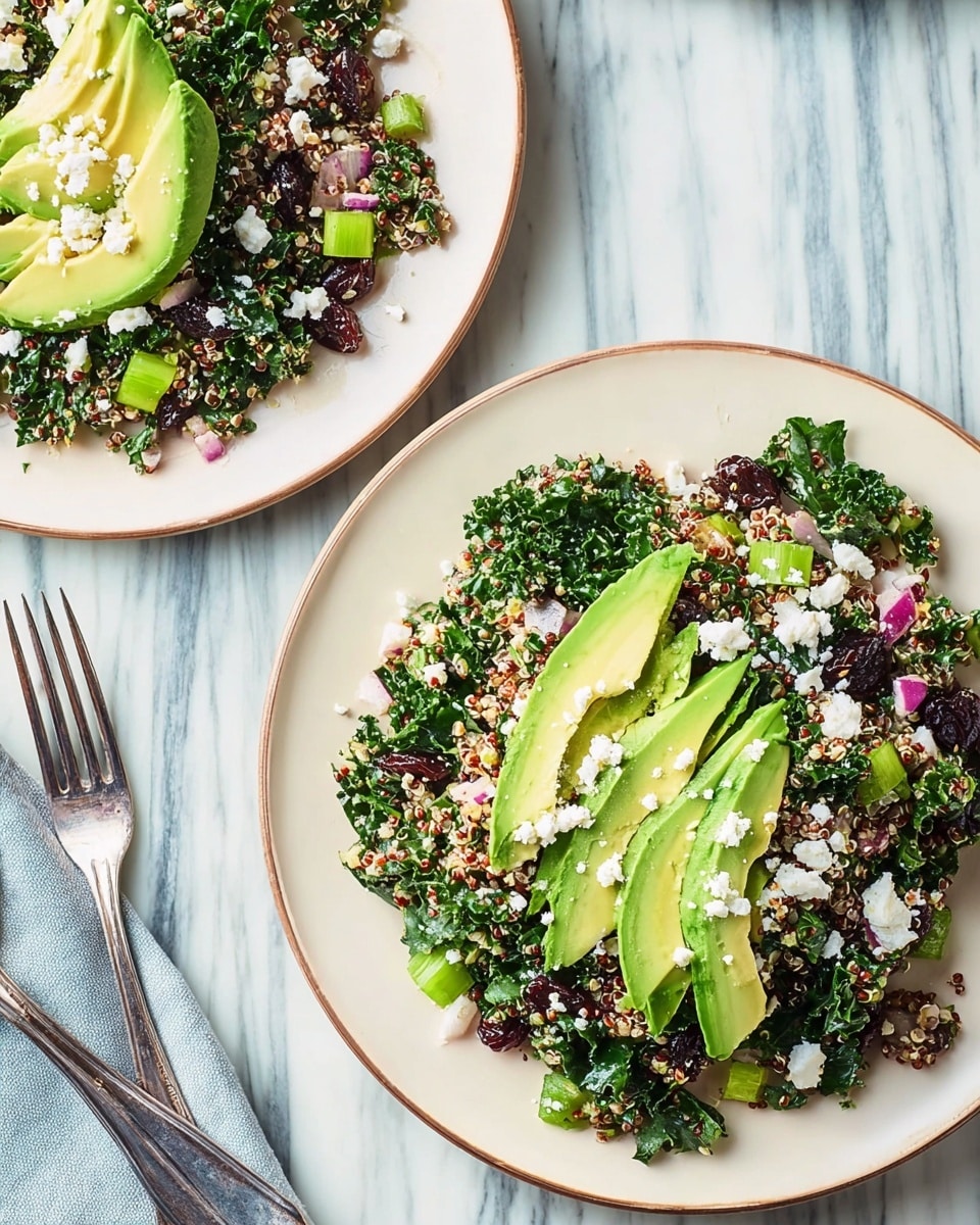 The image shows two white plates on a white marbled surface, each filled with a salad that has multiple layers. The base is a mix of finely chopped dark green kale and small light yellow quinoa seeds. Mixed in are small pieces of red onion and celery, adding bits of purple and light green throughout. On the top center of the salad are neatly fanned slices of bright green avocado, sprinkled with crumbled white cheese. One plate has a silver fork resting on its edge, and a woman's hand is holding the fork on the other plate. The whole scene is bright and fresh. photo taken with an iphone --ar 4:5 --v 7