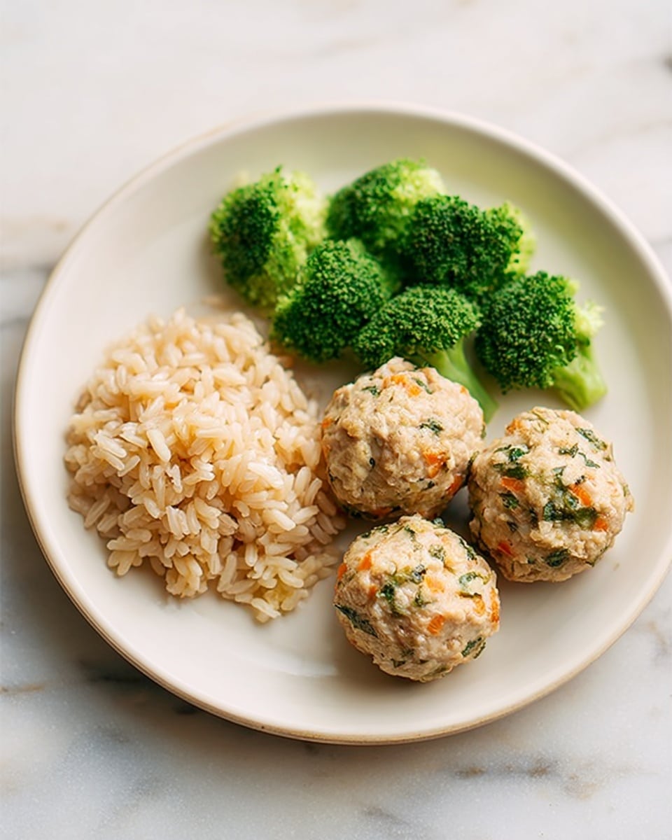 The image shows a white plate with three main parts of food arranged neatly: on the left side, there is a serving of light brown rice with a soft texture, in the center and right side, there are three round meatballs with a light brown color mixed with small green and orange bits, and at the top left corner, there are several bright green broccoli florets with a slightly rough texture. The plate is set on a white marbled surface. photo taken with an iphone --ar 4:5 --v 7