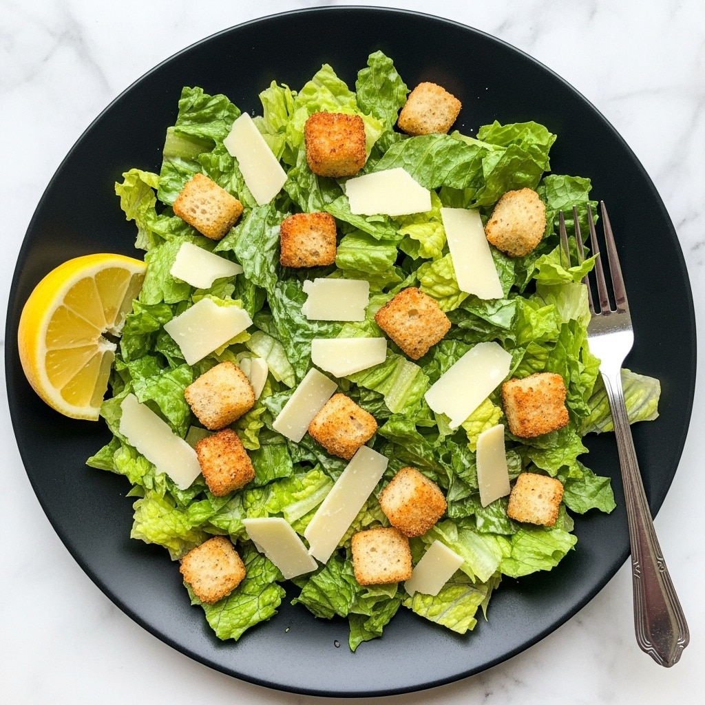 A black round plate holds a fresh Caesar salad with a mix of large and torn green romaine lettuce leaves forming the first layer, scattered with golden-brown crunchy croutons as the second layer. On top, thin, pale yellow slices of Parmesan cheese are spread out evenly. A small wedge of yellow lemon is placed on the edge of the plate, and a silver fork rests on the top right side. The plate is set on a white marbled background. photo taken with an iphone --ar 4:5 --v 7