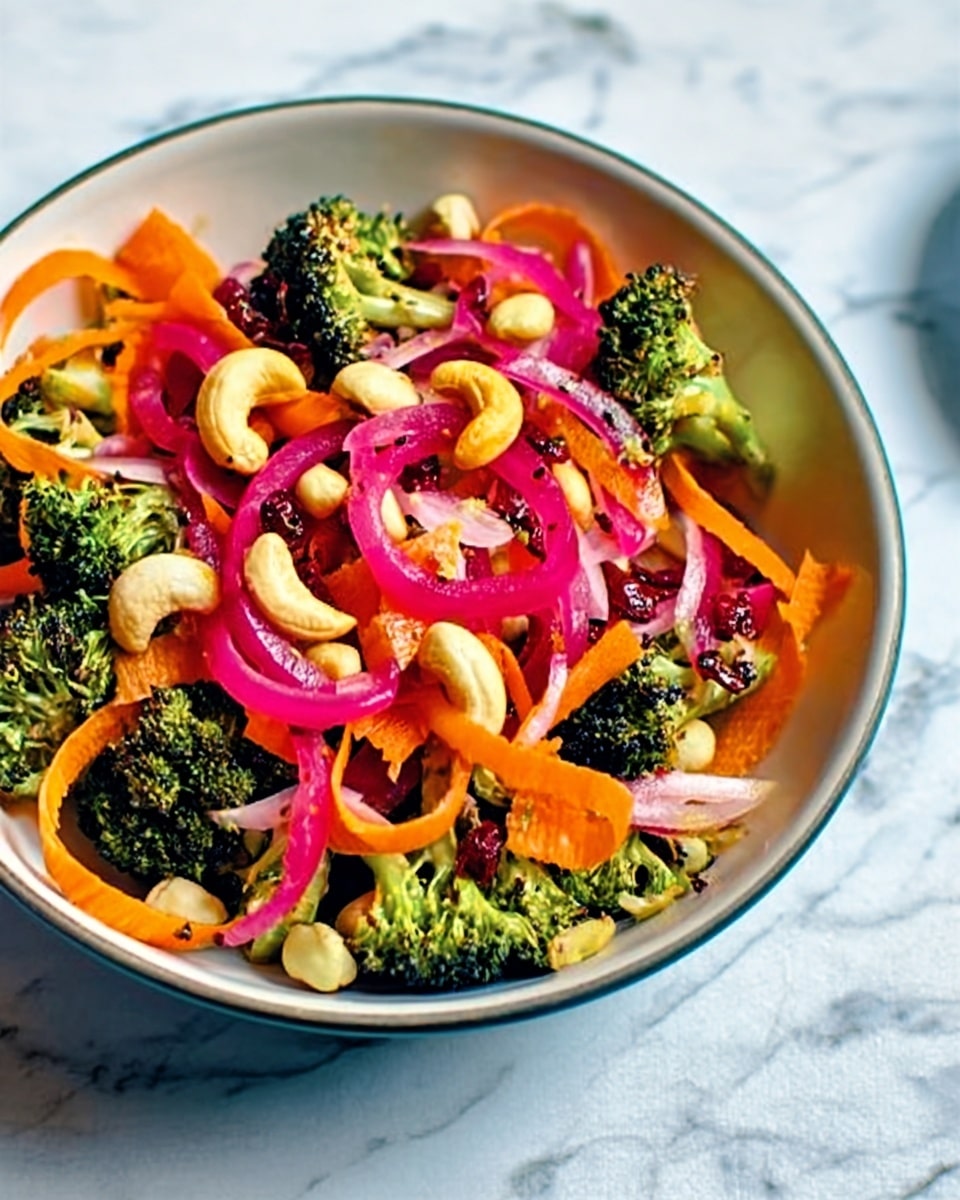 A white bowl filled with a fresh salad containing bright green broccoli florets, orange carrot ribbons, and thin pale yellow strips of cheese or similar ingredient. Scattered over the top are thin, curly, pickled red onion rings and small white cashew nuts. There are also some dark, small dried fruits or nuts mixed in, adding contrast. The bowl is placed on a white marbled surface, with a wooden spoon holding some salad to the left and a small white bowl with more pickled red onions on the right. photo taken with an iphone --ar 4:5 --v 7