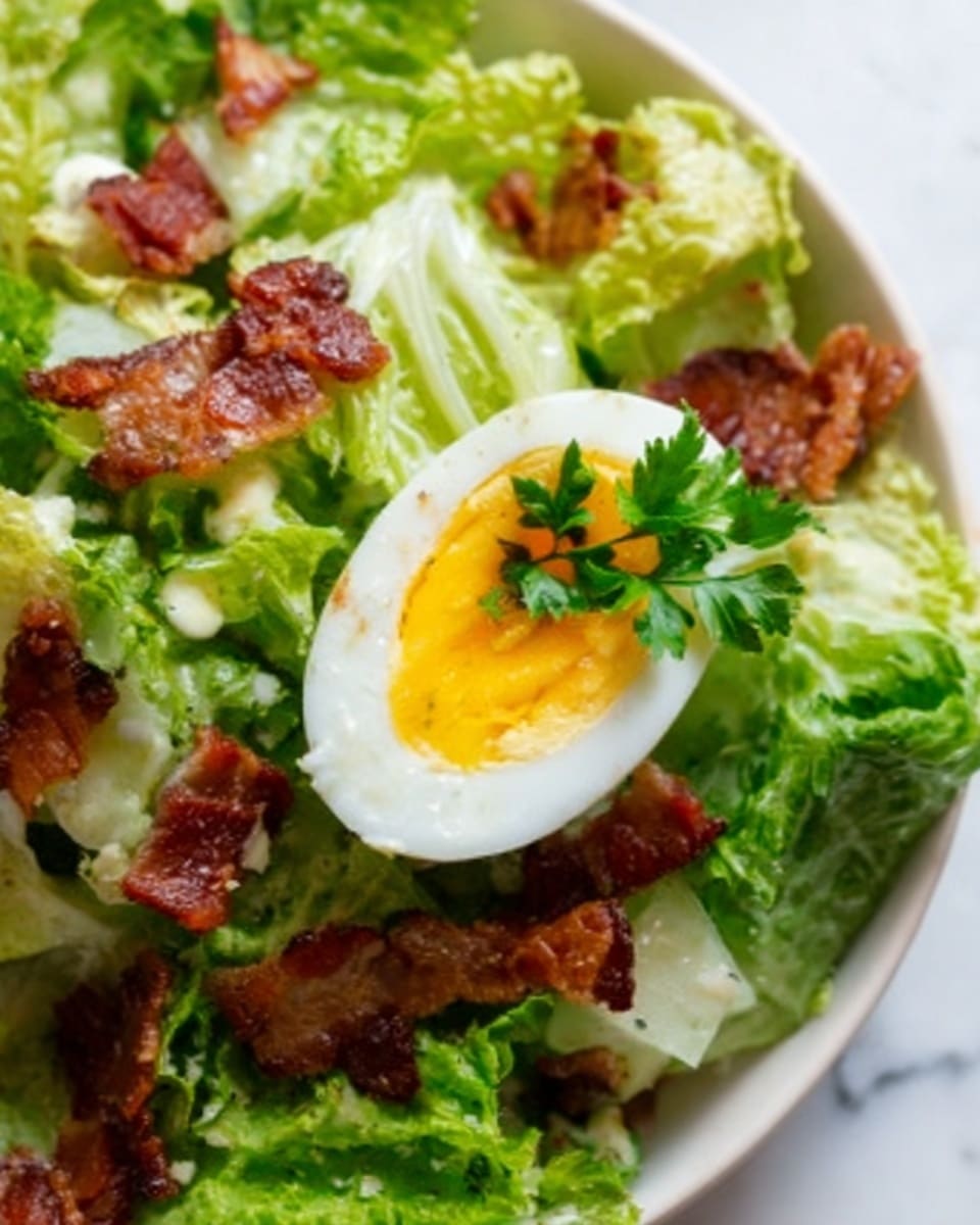 The image shows a close-up of a salad with green lettuce leaves as the base layer. On top of the lettuce are pieces of crispy bacon with a reddish-brown color and some white croutons scattered around. In the center of the image, there is a halved boiled egg with a bright yellow yolk and a touch of green garnish on top. The dish is placed on a white plate, and the background is a white marbled texture. The photo taken with an iphone --ar 4:5 --v 7