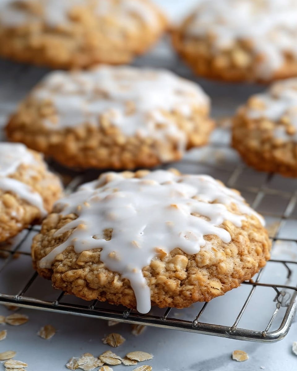 The image shows several round oatmeal cookies with a rough, textured surface from the oats, each topped with a layer of white icing that is spread unevenly, dripping slightly around the edges. The cookies are resting on a metal cooling rack above a white marbled surface, with scattered oats around some cookies. The cookies have a warm golden-brown color with visible oat pieces, and the icing appears smooth and glossy, contrasting with the rough cookie texture. The focus is on the front cookie, which is centered and closest to the viewer, with the others softly blurred in the background. photo taken with an iphone --ar 4:5 --v 7